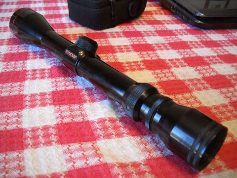 1986 Ford Bronco II - A Simmons rifle scope rests on a red and white checkered tablecloth next to a black case and a laptop.