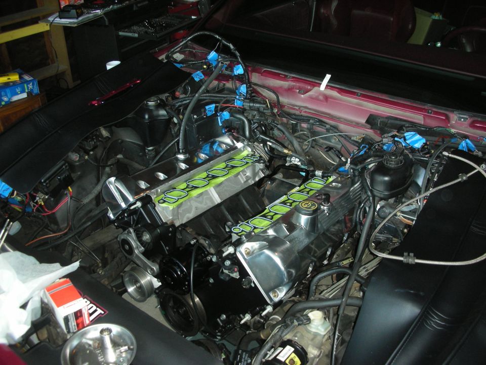 Engine bay with chrome valve covers and green gaskets during rebuild