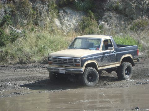 1986 Ford Bronco - This Ford Bronco is navigating a wet, muddy off-road path.