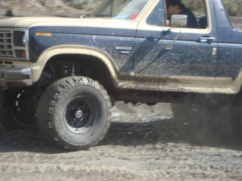 1986 Ford Bronco - This 1986 Ford Bronco is shown in a 3/4 front view, navigating through muddy terrain.