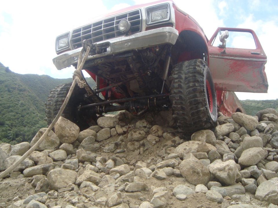 Red off-road truck with open door, front view, stuck on rocks