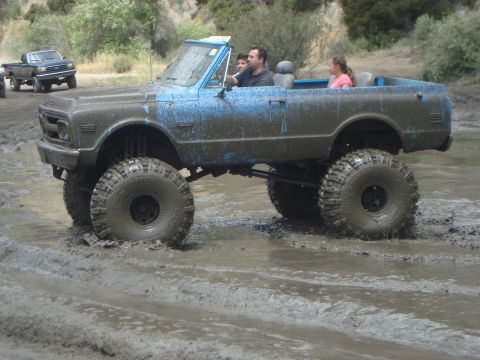 1986 Ford Bronco - A heavily modified Chevrolet K5 Blazer navigates a muddy terrain with its occupants.