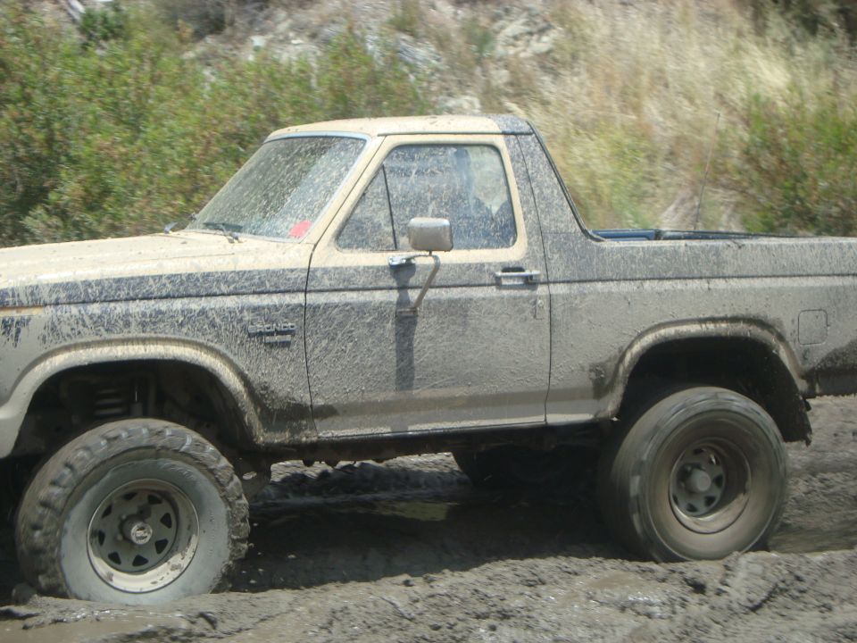 Mud-covered 1986 Ford Bronco side view, stuck in mud off-road