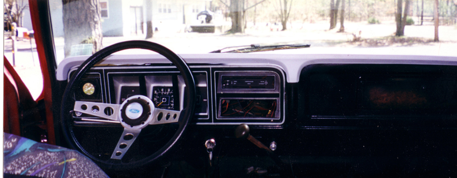 Vintage Ford truck dashboard with three-spoke wheel and aftermarket radio