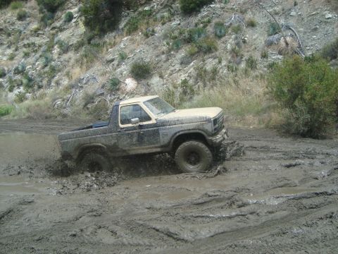 1986 Ford Bronco - This 1980s Ford Bronco is deep in the mud, struggling to get through the mire.