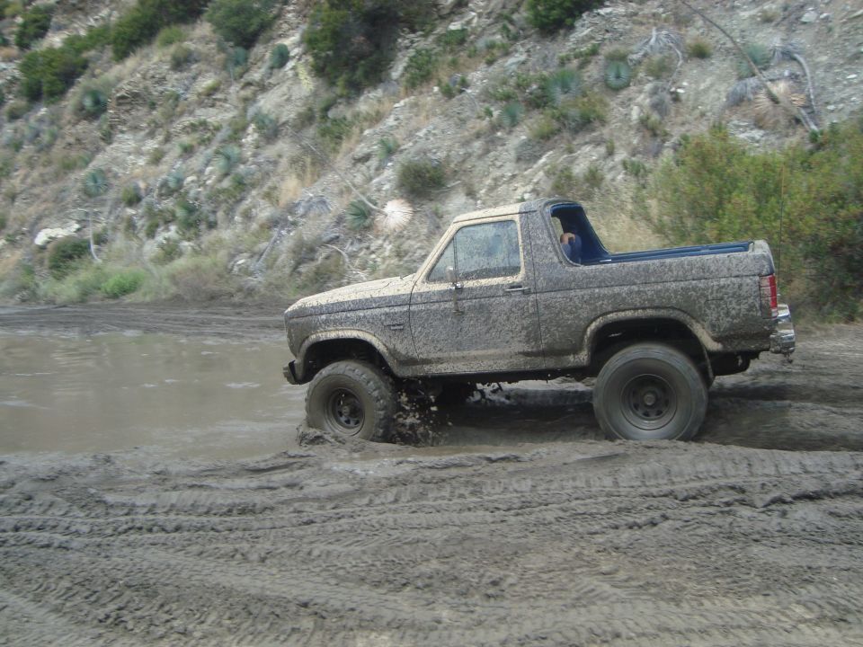 Muddy SUV driving through a muddy track with tires splashing