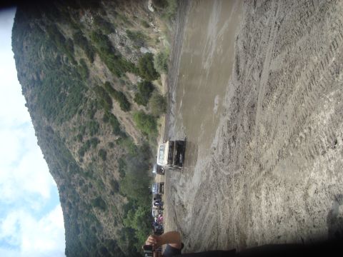 1986 Ford Bronco - Multiple off-road vehicles are seen driving through a muddy terrain on a sunny day.