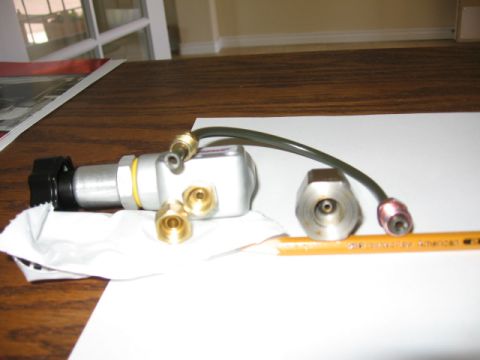 1995 Ford Bronco - A brake proportioning valve is shown with its associated fittings and a pencil for size comparison.