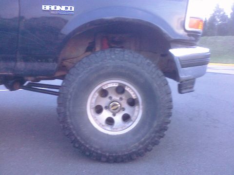 1995 Ford Bronco - Close-up of the front wheel and fender of a Ford Bronco, with 'BRONCO' badging visible.