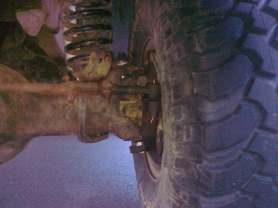 Close-up of a large, knobby tire and rusty suspension components