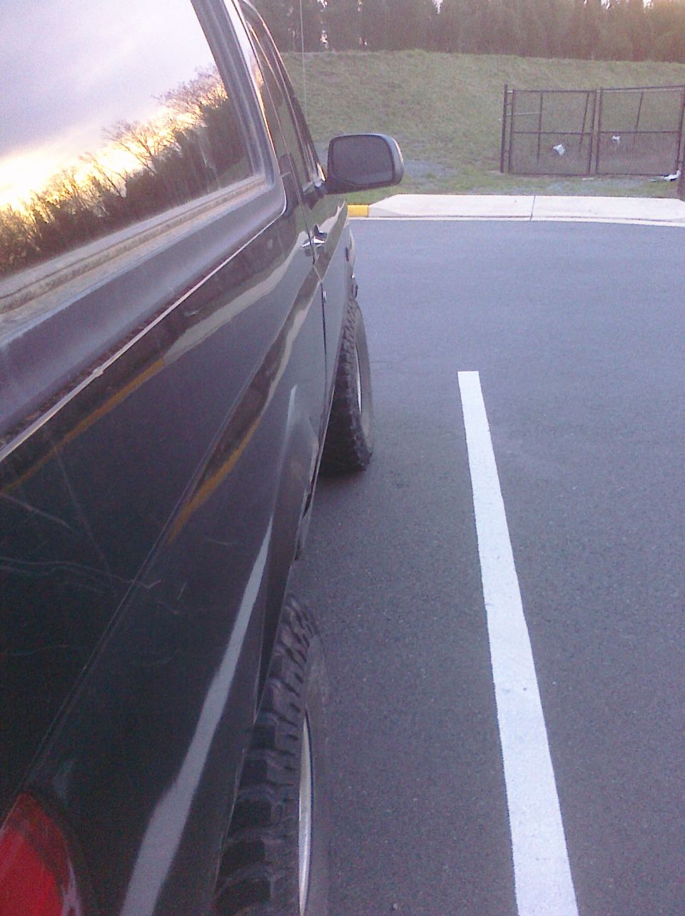 Dark SUV parked in a lot, side view showing the rear wheel and part of the door