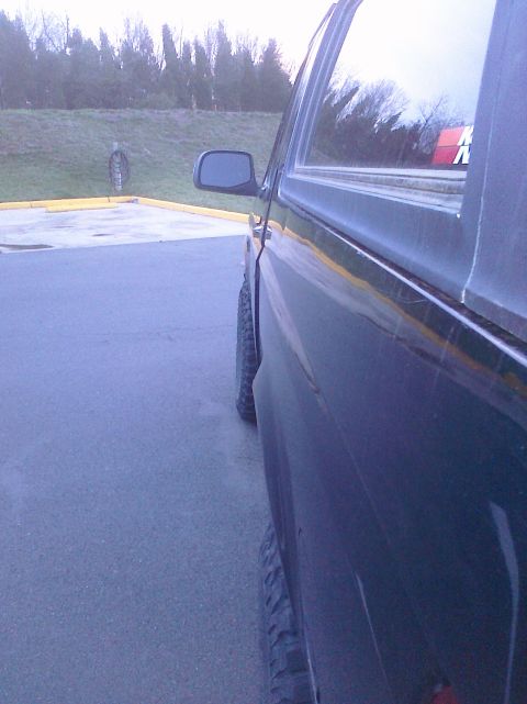 1995 Ford Bronco - Side view of a dark SUV with lifted suspension and off-road tires, parked outdoors.