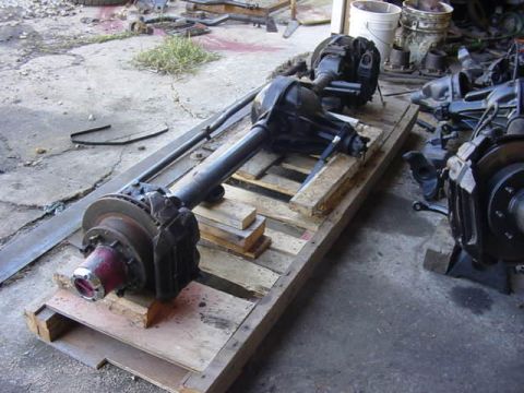1992 Ford Bronco - Multiple vehicle axle assemblies and brake components are laid out on wooden pallets in an outdoor setting.