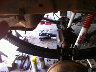 1995 Ford Bronco - Close-up view of the rear suspension components, including leaf springs and shocks, with another vehicle in the background.