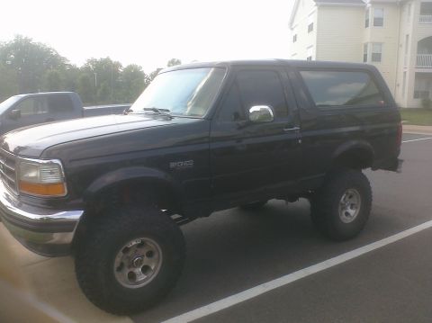 1995 Ford Bronco - This black 1995 Ford Bronco features a lifted suspension and is shown from a 3/4 front angle.