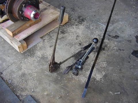 1992 Ford Bronco - A red and silver hub assembly rests on wooden pallets alongside two strapping tools on a concrete floor.