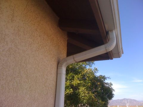 1968 Ford Mustang - A white gutter and downspout system is visible on the side of a building under a clear blue sky.