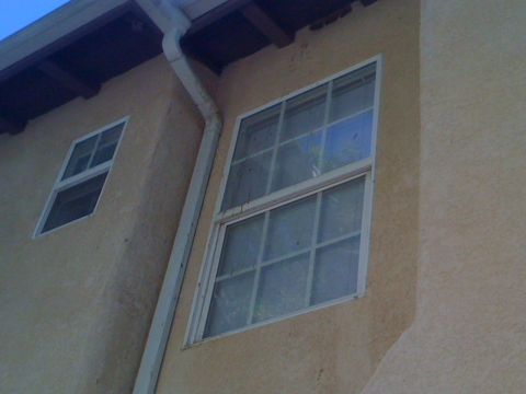 1968 Ford Mustang - Exterior view of a building's wall with two windows and a downspout.