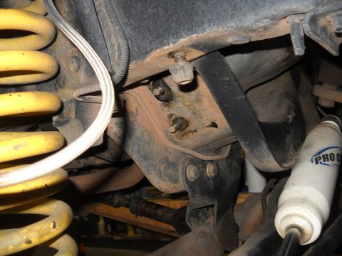 1986 Ford Bronco II - Close-up view of vehicle suspension components, including a yellow coil spring and a white shock absorber.