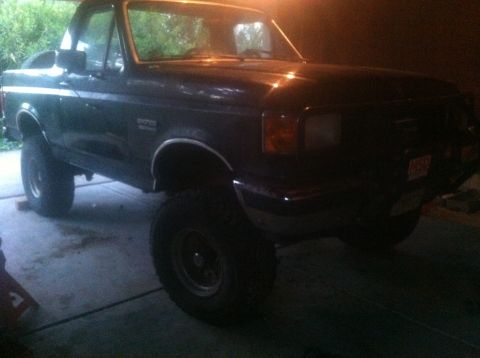 1990 Ford Bronco - This lifted Ford Bronco is shown from a three-quarter front view, parked inside a garage.