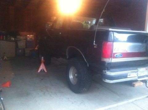 1990 Ford Bronco - This black 1990 Ford Bronco is shown in a garage, possibly undergoing maintenance or modification with its lifted suspension.