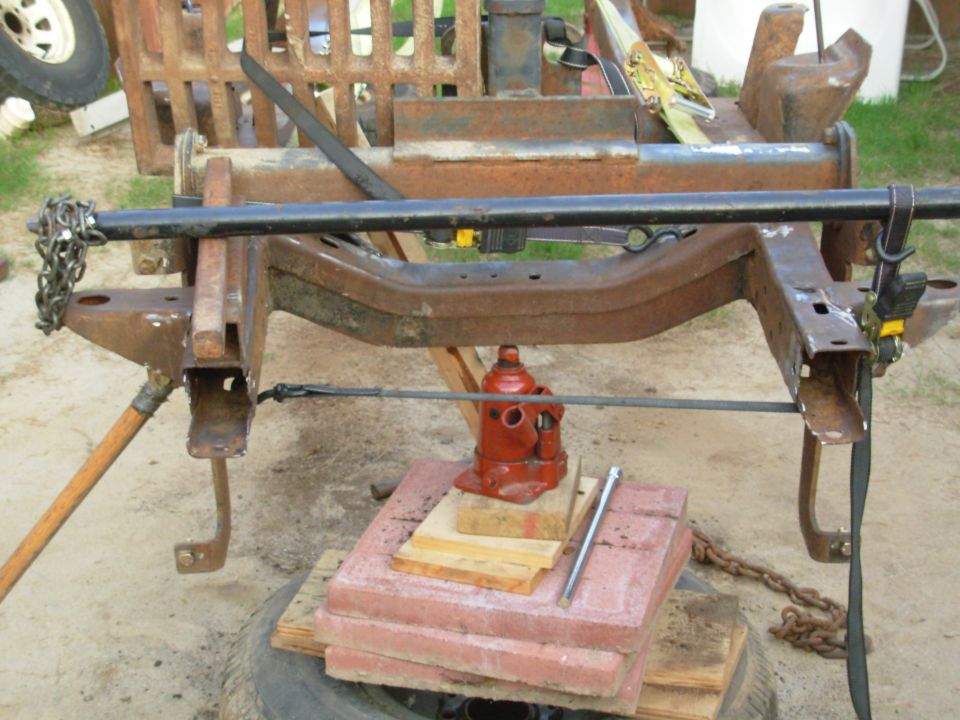 SOLD Apr22 To straighten the core support brackets, I'm using my rock bar (an Expedition torsion bar) to pry them up.  I'm using the ratchet strap so I don't pry the frame off the jack & stands.  All the weights are there for the hammering I've been doing.  That's a fullsize Bronco Class 4 hitch receiver straddling the early Bronco frame.
IF THE IMAGE IS TOO SMALL, click it.