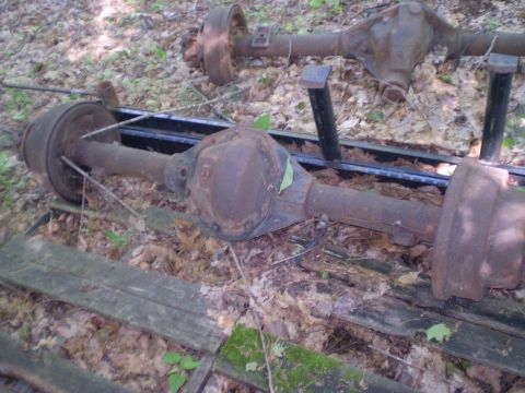 1979 Ford Bronco - Pair of old vehicle axles, likely for sale, shown in an outdoor setting.