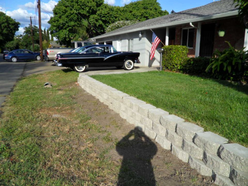 Black 1955 Ford Crown Victoria parked in front of a house with an American flag