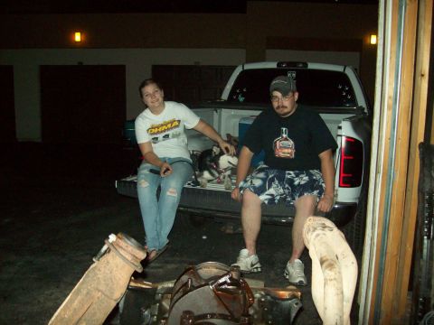 1985 Ford Bronco - A couple and their dog relax in the bed of a pickup truck at night, with garage doors in the background.