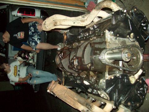 1985 Ford Bronco - Engine assembly with timing chain and exhaust components is the focus of this garage scene.