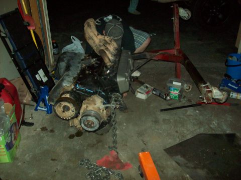 1985 Ford Bronco - Engine assembly being worked on, suspended by an engine stand in a workshop environment.