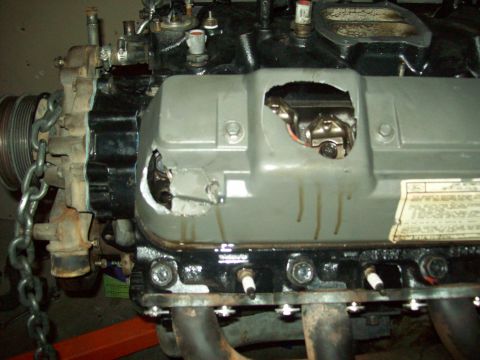 1985 Ford Bronco - The engine's valve cover has been cut open, revealing internal components and showing signs of oil leakage.