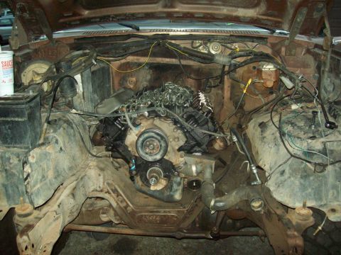 1985 Ford Bronco - The engine bay is exposed, revealing the chassis and various mechanical parts during a rebuild.