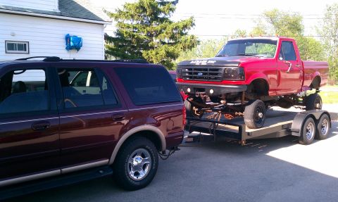 1999 Ford Expedition - Maroon Ford Expedition tows a red Ford pickup truck on a trailer.