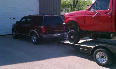 1999 Ford Expedition - A maroon Ford Expedition is towed on a trailer, with a red truck also on the trailer.