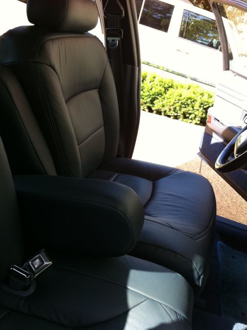 1999 Ford Crown Victoria - The interior of a car shows black leather seats and a seatbelt.