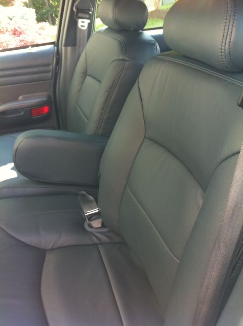 1999 Ford Crown Victoria - Interior view of the front seats in a 1999 Ford Crown Victoria, dark leather upholstery and a center console armrest.