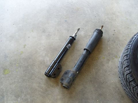 2007 Ford Mustang - Two car shock absorbers and a tire are shown on a concrete floor.