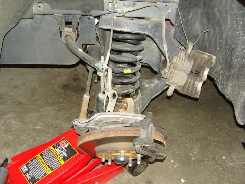 2007 Ford Mustang - The image shows a close-up of a vehicle's suspension and brake system, supported by a red jack.