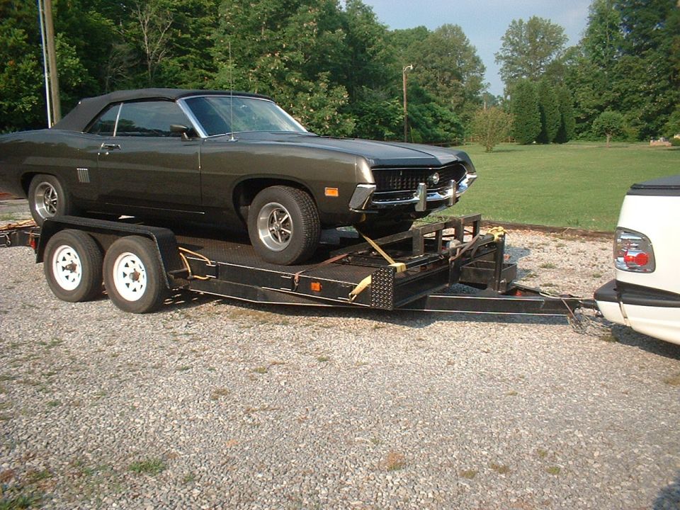 1970 Ford Torino convertible being transported on a dual-axle trailer, hitched to a white pickup truck
