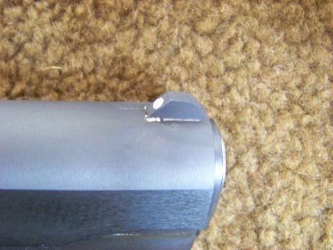 1995 Mercury Grand Marquis - Close-up of a gun's barrel and front sight, placed on a textured surface.