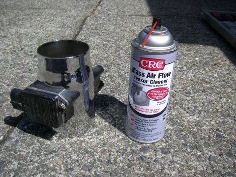 1990 Ford Bronco - Mass air flow sensor and cleaner spray sitting on a concrete surface.
