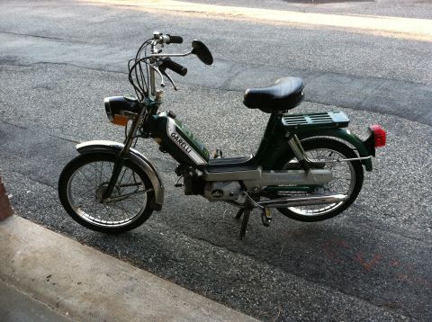 1981 Garelli Rally Sport - This green Garelli moped is parked on a street, showing its side profile.