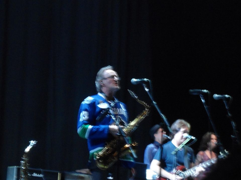 Musicians performing on stage with saxophones and guitars