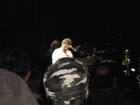 1989 Ford Bronco - A keyboardist performs on stage in front of a crowd, with other band members visible in the background.