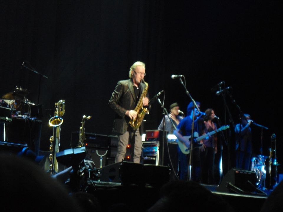 Band performing live on stage with a saxophonist in the foreground