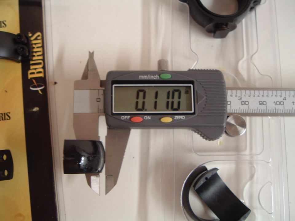 Digital caliper measuring a small black cylindrical part. The caliper reads 0.110 inches