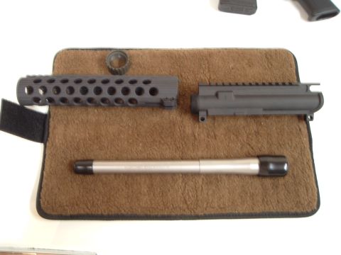 1995 Mercury Grand Marquis - Disassembled components of an AR-15 rifle are arranged on a textured mat.