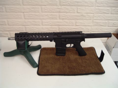 1995 Mercury Grand Marquis - A black rifle is displayed on a table with a brick wall in the background.