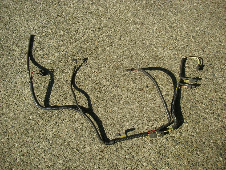 Removed black taped wiring harness with plastic connectors laid out on concrete